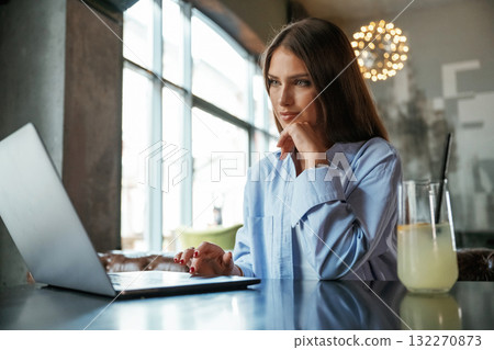 Positive facial expression. Beautiful woman with laptop is in the bar Positive facial expression. Beautiful woman with laptop is in the bar 132270873