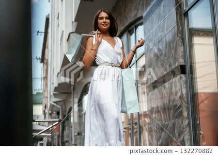 Taking a walk. Stylish woman is with shopping bag outdoors near the building Taking a walk. Stylish woman is with shopping bag outdoors near the building 132270882