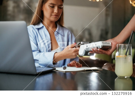 Using smartphone. Woman is paying for the service in the restaurant Using smartphone. Woman is paying for the service in the restaurant 132270916