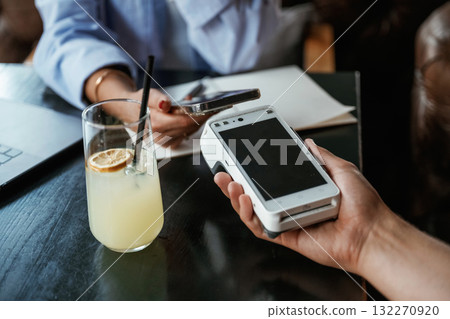 Contactless transfer. Woman is paying for the service in the restaurant Contactless transfer. Woman is paying for the service in the restaurant 132270920