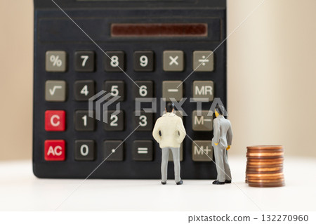 兩位身著西裝的微型商人站在計算器前 132270960