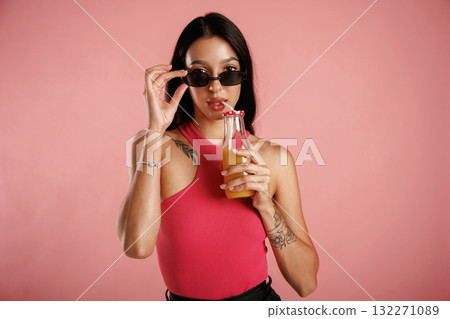 Orange juice in glass. Beautiful young woman is against background Orange juice in glass. Beautiful young woman is against background 132271089