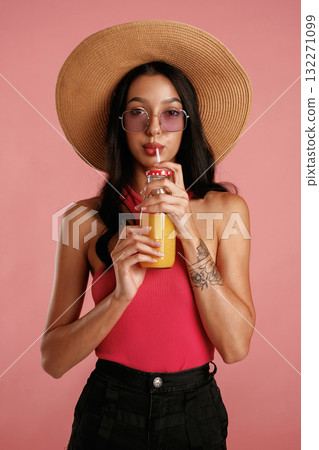 Drinking orange juice. Beautiful young woman is against background Drinking orange juice. Beautiful young woman is against background 132271099
