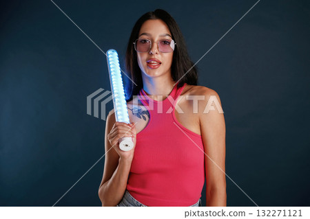Neon lighting equipment in hands. Beautiful young woman is against background Neon lighting equipment in hands. Beautiful young woman is against background 132271121