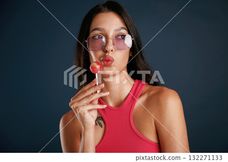 Sweet and tasty lollipop. Beautiful young woman is against background 132271133