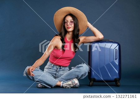 Waiting, sitting with suitcase. Beautiful young woman is against background 132271161