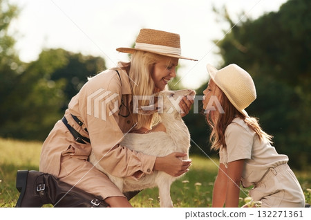 In straw hats. Mother and daughter are together on the farm with goat In straw hats. Mother and daughter are together on the farm with goat 132271361