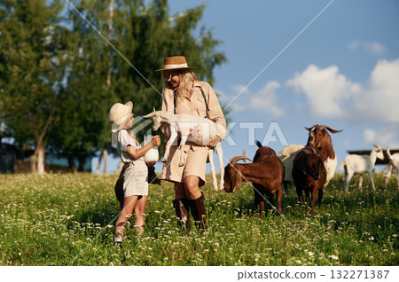 Mother and daughter are together on the farm with goats Mother and daughter are together on the farm with goats 132271387