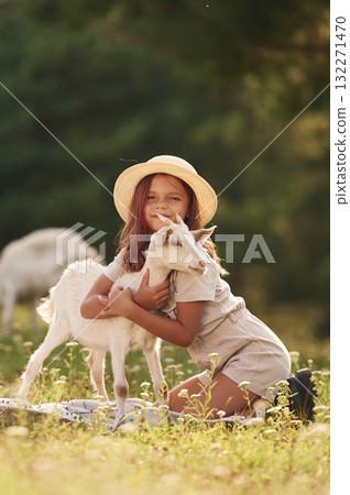 Embracing the animal. Little girl is on the field with goats Embracing the animal. Little girl is on the field with goats 132271470