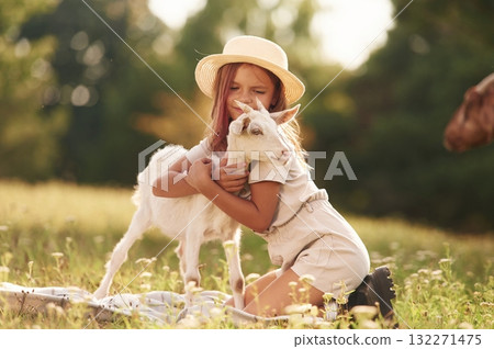 Hugs time. Little girl is on the field with goat Hugs time. Little girl is on the field with goat 132271475