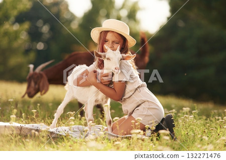 Hugs time. Little girl is on the field with goats Hugs time. Little girl is on the field with goats 132271476