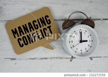 Managing conflict text with alarm clock on wooden background 132271550