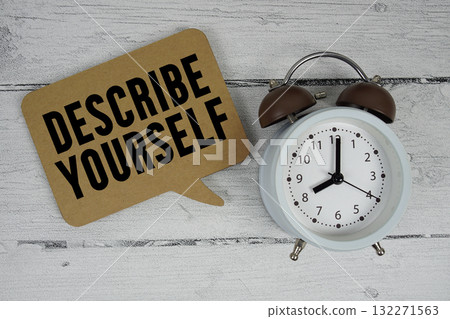 Describe yourself text with alarm clock on wooden background Describe yourself text with alarm clock on wooden background 132271563