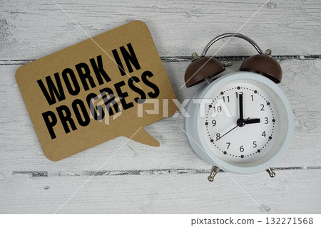 Work in progress text with alarm clock on wooden background Work in progress text with alarm clock on wooden background 132271568