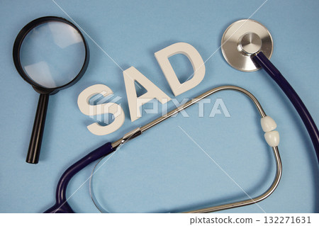 SAD abbreviation of Social Anxiety Disorder alphabet letters with magnifying glass and stethoscope on blue background SAD abbreviation of Social Anxiety Disorder alphabet letters with magnifying glass and stethoscope on blue background 132271631