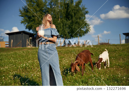 Young woman is on the field, farm, with the goats 132271696