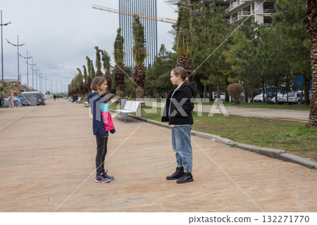 Two young girl children standing on the street and looking at each other Two young girl children standing on the street and looking at each other 132271770