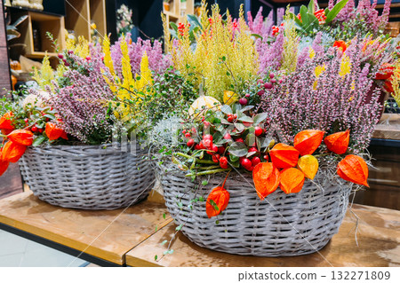 Handmade autumn flower baskets with heather, berries, and orange lantern blooms displayed in a store. Gifting culture, sustainable celebration practices, zero-waste decor, artisanal product 132271809