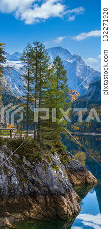 Peaceful autumn Alps mountain lake with clear transparent water and reflections. Gosauseen or Vorderer Gosausee lake, Upper Austria. Dachstein summit and glacier in far. 132271920