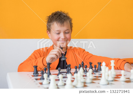 Cheerful school boy student playing chess in the classroom. Child with chess indoor Cheerful school boy student playing chess in the classroom. Child with chess indoor 132271941