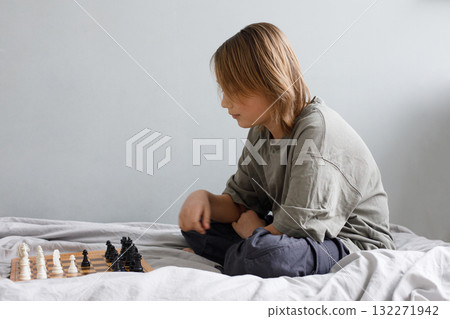 Thinking child boy playing chess board game indoor. Kid 11 years old with chess at home Thinking child boy playing chess board game indoor. Kid 11 years old with chess at home 132271942