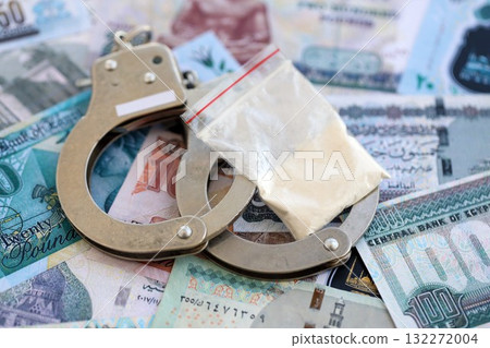 Egyptian pound currency money bills and cocaine pack with handcuffs close up. The concept of drug crimes 132272004