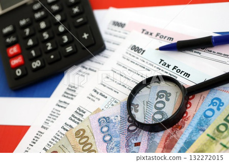 Thai baht money bills and calculator with tax form on flag close up. Taxation and accounting concept Thai baht money bills and calculator with tax form on flag close up. Taxation and accounting concept 132272015