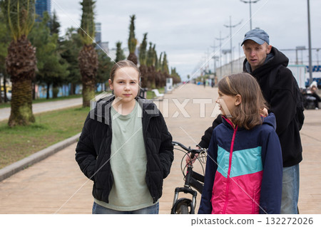 Cute child girls with bicycle walking with her father outdoors Cute child girls with bicycle walking with her father outdoors 132272026