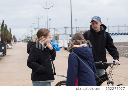 Pretty child girls 10 and 12 years old and her father with bicycle walking outdoors Pretty child girls 10 and 12 years old and her father with bicycle walking outdoors 132272027