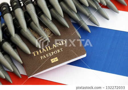 Thai passport and rifle bullets on flag close up. The concept of warfare and gun selling Thai passport and rifle bullets on flag close up. The concept of warfare and gun selling 132272033