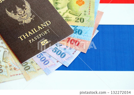 Thai baht currency money bills and passport lies on flag close up. The concept of travel and vacation Thai baht currency money bills and passport lies on flag close up. The concept of travel and vacation 132272034