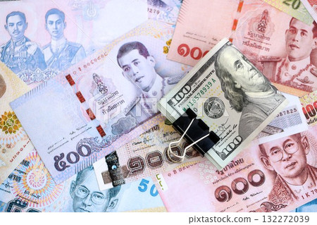 Thai baht currency money bills and bunch of us dollar banknotes close up. The concept of economics and currency exchange Thai baht currency money bills and bunch of us dollar banknotes close up. The concept of economics and currency exchange 132272039