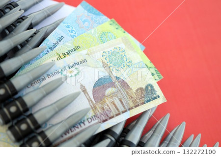 Bahraini dinar currency money bills and rifle bullets on flag close up. The concept of warfare and gun selling Bahraini dinar currency money bills and rifle bullets on flag close up. The concept of warfare and gun selling 132272100