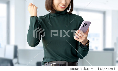 一位微笑的女人/女商人高興地看著她的智慧型手機 一位微笑的女人/女商人高興地看著她的智慧型手機 132272261