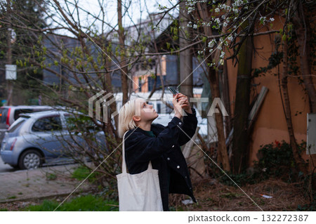 Beautiful woman making pictures with smartphone on spring city street outdoors. \ Beautiful woman making pictures with smartphone on spring city street outdoors. \ 132272387