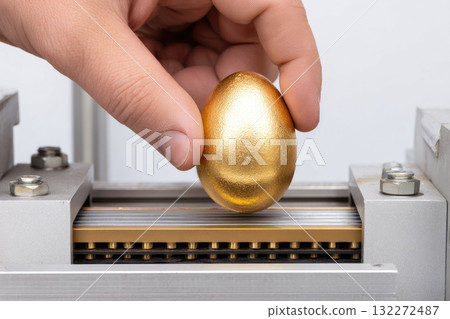 Hand holding golden egg above metal machine, minimal modern surreal concept, symbolizing value, wealth, investment, and creativity in industrial setting, with focus on innovation and uniqueness 132272487