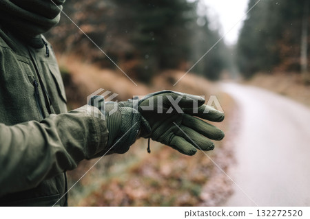 Hand adjusting green hiking glove on forest path outdoor adventure autumn minimal style cold weather preparing for journey nature tranquil mood Hand adjusting green hiking glove on forest path outdoor adventure autumn minimal style cold weather preparing for journey nature tranquil mood 132272520