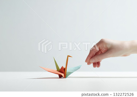 Hand arranging colorful origami paper crane on white table, minimalistic background, creative art, peaceful atmosphere, delicate paper folding, vibrant colors, focus on craftsmanship Hand arranging colorful origami paper crane on white table, minimalistic background, creative art, peaceful atmosphere, delicate paper folding, vibrant colors, focus on craftsmanship 132272526
