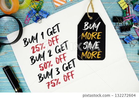 Buy 1 get 25%, Buy 2 get 50%, Buy 3 get 75% text on a notepad paper and Buy More Save More with price tag surrounded by office supplies and magnifying glass on a blue wooden surface Buy 1 get 25%, Buy 2 get 50%, Buy 3 get 75% text on a notepad paper and Buy More Save More with price tag surrounded by office supplies and magnifying glass on a blue wooden surface 132272604