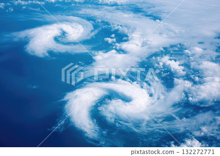 Aerial view of clouds forming spiral patterns over ocean, dramatic swirling shapes, blue sky, natural weather phenomenon, peaceful atmosphere Aerial view of clouds forming spiral patterns over ocean, dramatic swirling shapes, blue sky, natural weather phenomenon, peaceful atmosphere 132272771