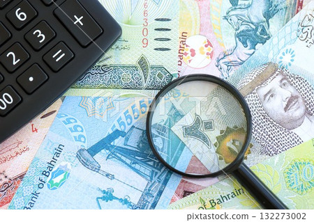 Bahraini dinar currency money bills and calculator with magnifying glass close up. The concept of taxation and money count Bahraini dinar currency money bills and calculator with magnifying glass close up. The concept of taxation and money count 132273002