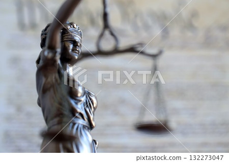Lady Justice statue with scales on background of US Constitution page close up. Lawsuit and punishment in United States 132273047