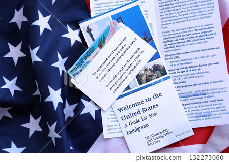 Permanent resident green card in envelope and guide for new immigrants lies on US flag close up 132273060