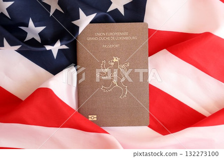 Luxembourg passport on big waving flag of United States of America close up. US Visa and immigration concept Luxembourg passport on big waving flag of United States of America close up. US Visa and immigration concept 132273100