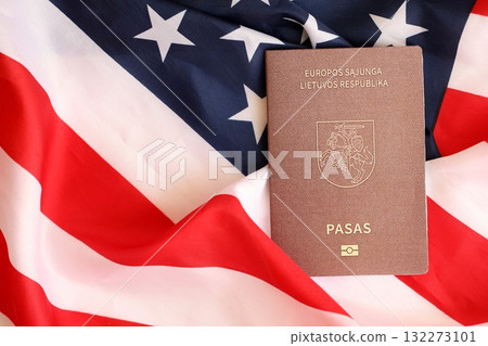 Lithuania passport on big waving flag of United States of America close up. US Visa and immigration concept Lithuania passport on big waving flag of United States of America close up. US Visa and immigration concept 132273101