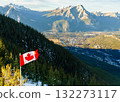 Canadian flag waves atop snow covered Canadian Rockies mountain with overlooking scenic town of Banff, Alberta in Canada 132273117