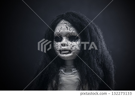 Portrait of a scary cracked doll with black hair on dark background 132273133