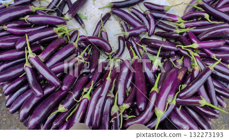 A vibrant display of long slender purple eggplants their glossy skin reflecting light piled high at a local produce stand 132273193