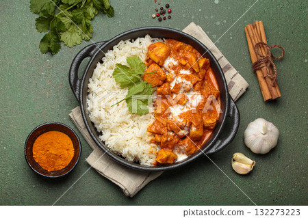 Indian dish chicken tikka masala served with rice and spices on green background top view Indian dish chicken tikka masala served with rice and spices on green background top view 132273223