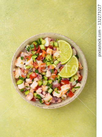 Peruvian seafood ceviche with shrimps, octopus, tomatoes, cucumber, and parsley in a bowl served with lime top view 132273227